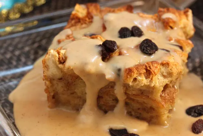 A piece of bread pudding with white sauce on top.