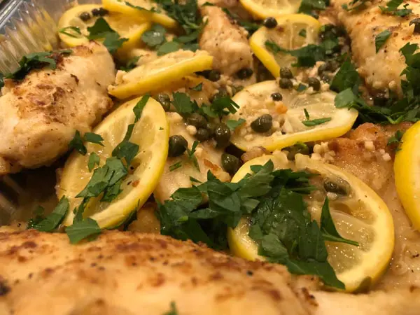 A close up of some lemon and parsley on top of chicken