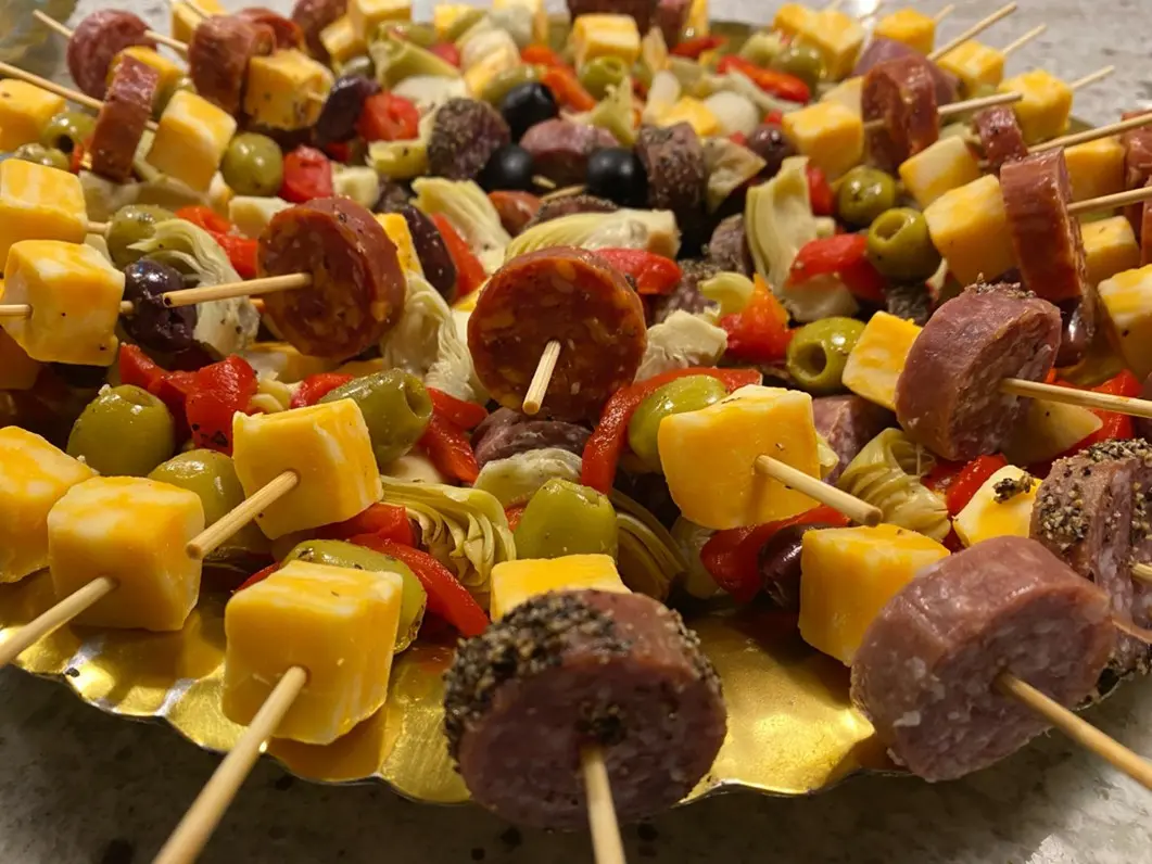 A plate of skewered food with cheese and sausage.