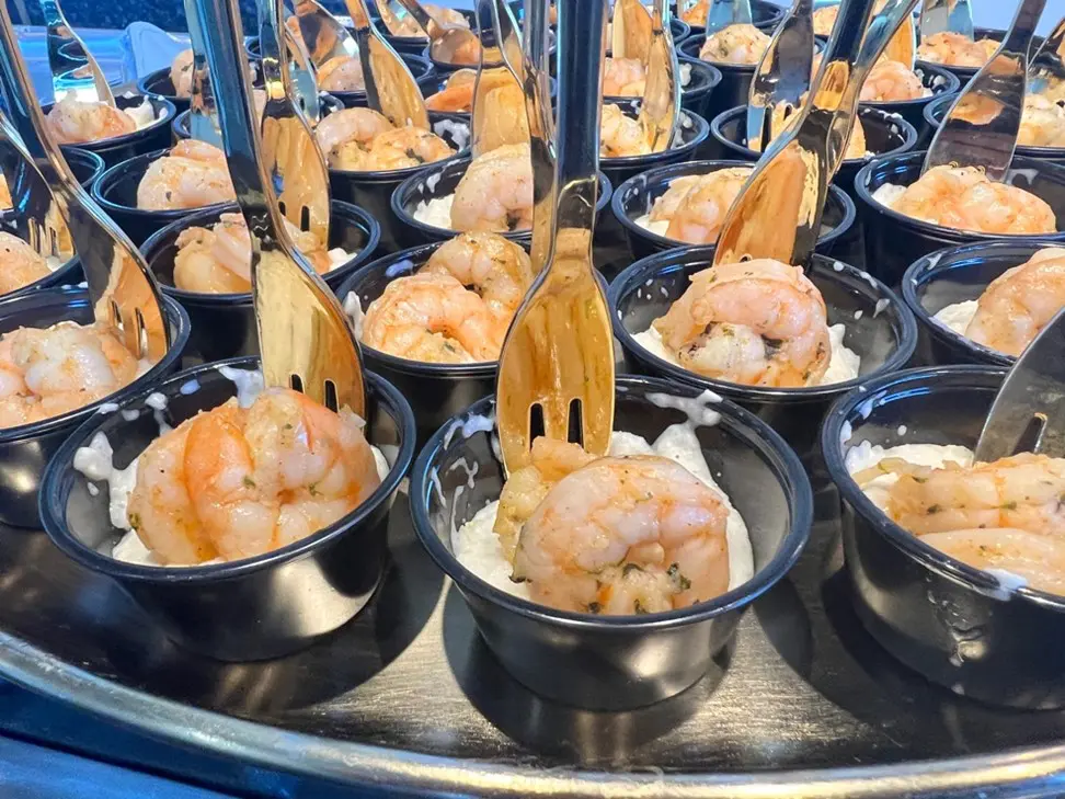 A tray of shrimp and rice with wooden utensils.