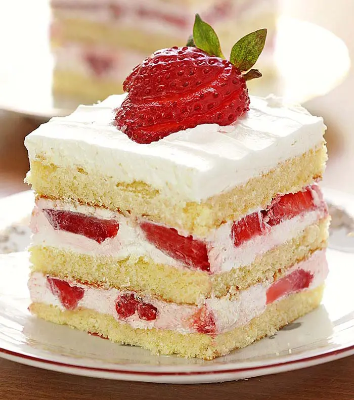 A piece of cake with white frosting and strawberries on top.