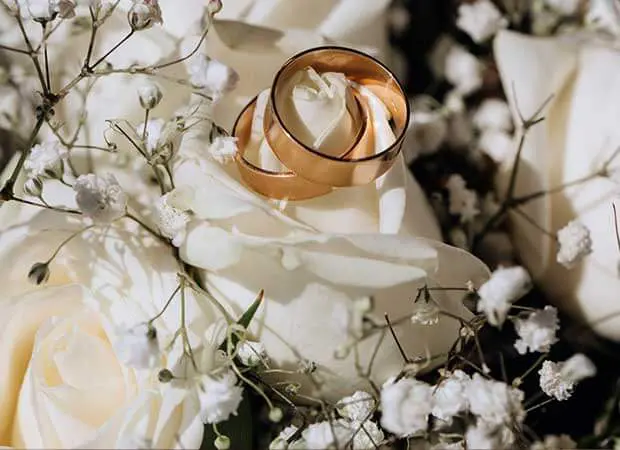 A gold wedding band sitting on top of white flowers.