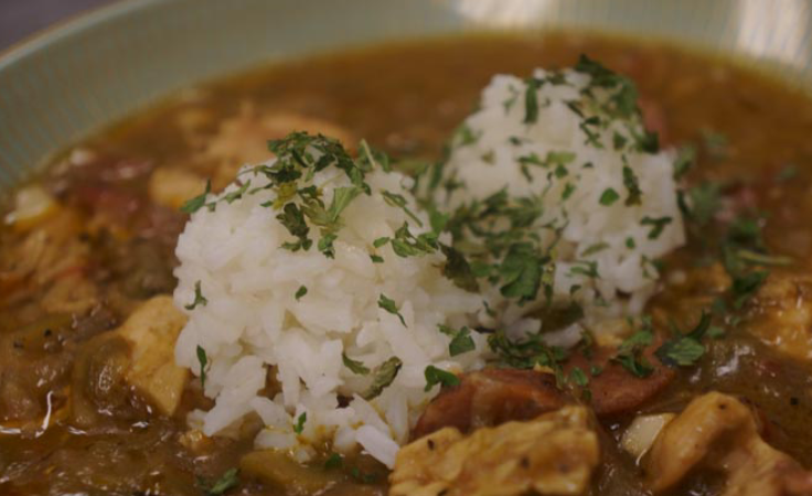 A bowl of rice and meat covered in gravy.