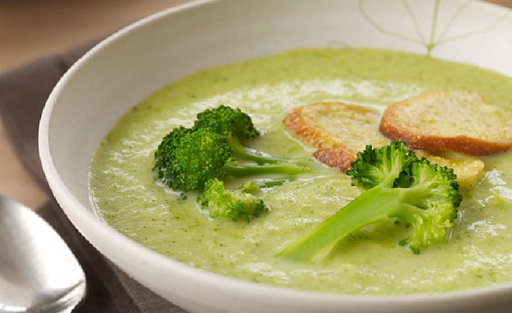 A bowl of broccoli soup with croutons.